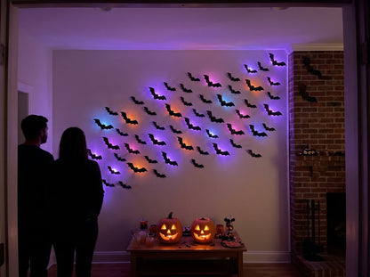 Halloween party in front of a glowing bat wall with carved pumpkins